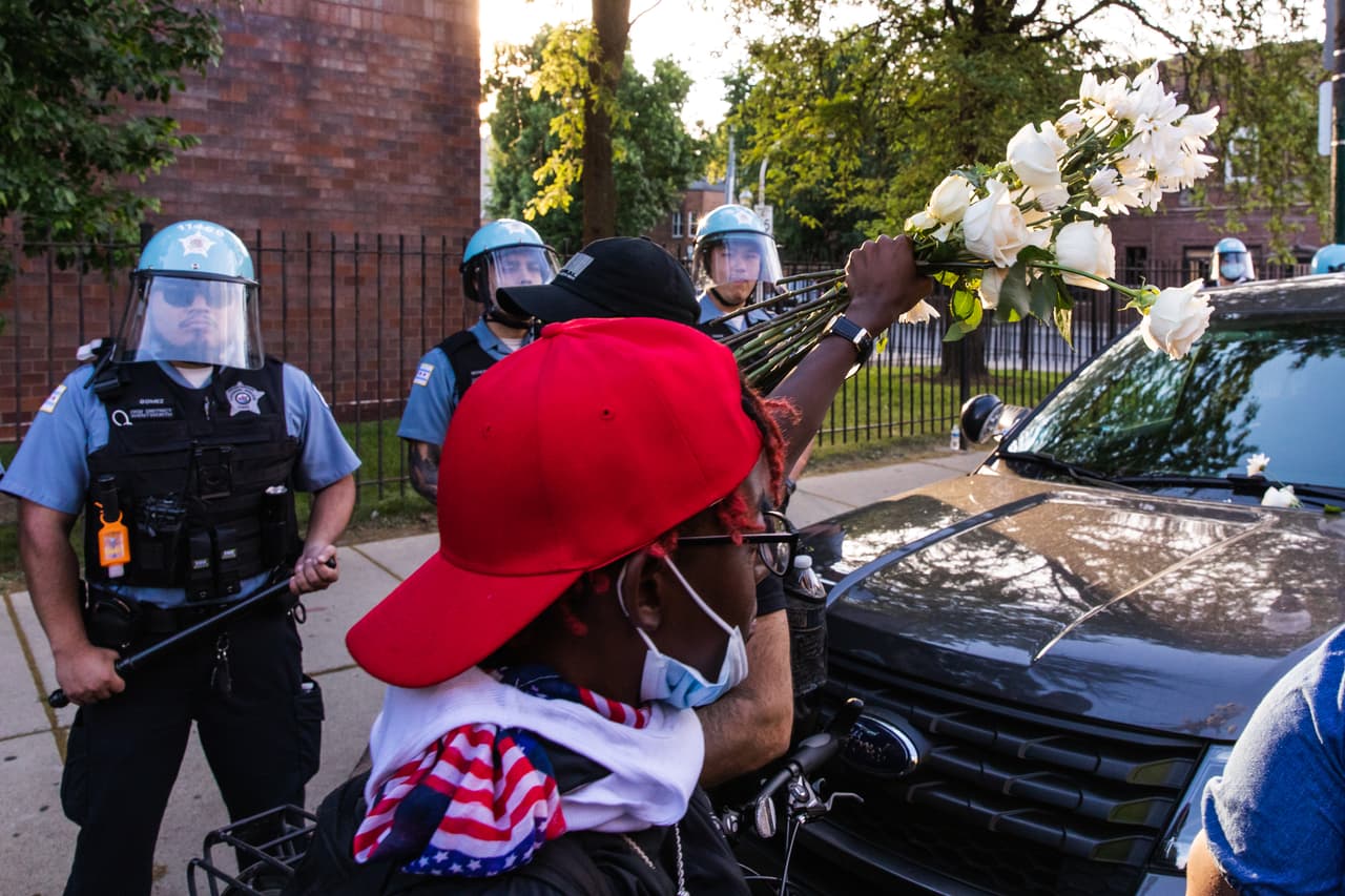 Los manifestantes ofrecen flores a un grupo de oficiales en Chicago, durante el deduodécimo día de protestas desde que George Floyd murió bajo la rodilla de un policía de Minneapolis.