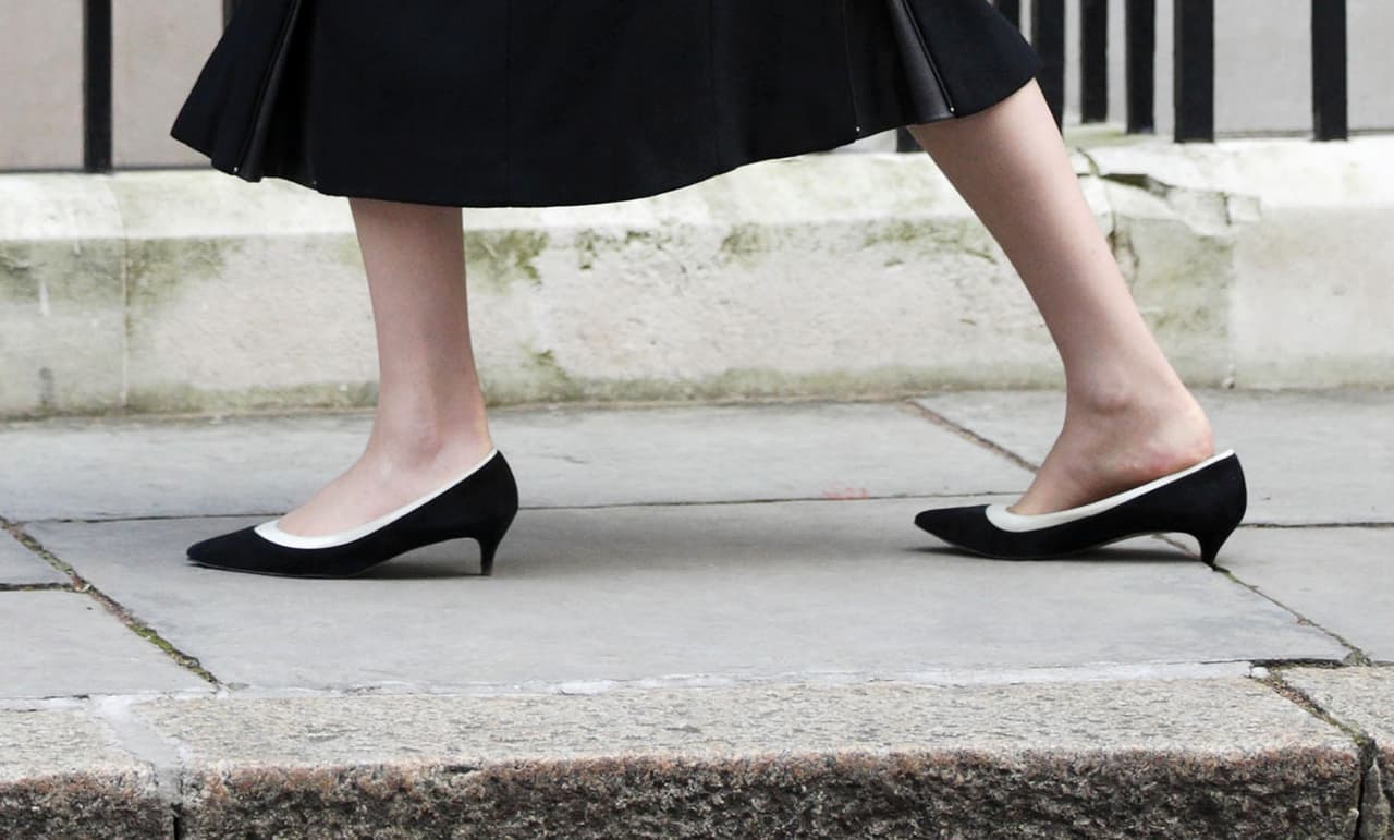 Como si fuera la mismísima Coco Chanel, la política sabe llevar faldas 'midi' con zapatillas de minúsculo tacón en combinación blanca y negra. Y como si fuera una mujer común se detiene a desatascar su tacón de uno de los bloques de concreto del número 10 de la calle Downing en donde se reúne el Gabinete en Londres.