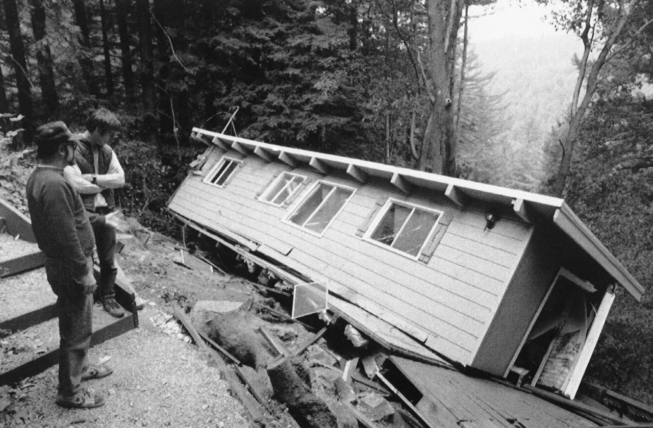 Bob Kubiatowicz y John Wooliscroft observan desconsolados lo que quedó que la casa de uno de sus vecinos en una colina de Boulder Cree. Según las autoridaes, el saldo de viviendas inhabitables tras el sismo fue de más de 16,000.
