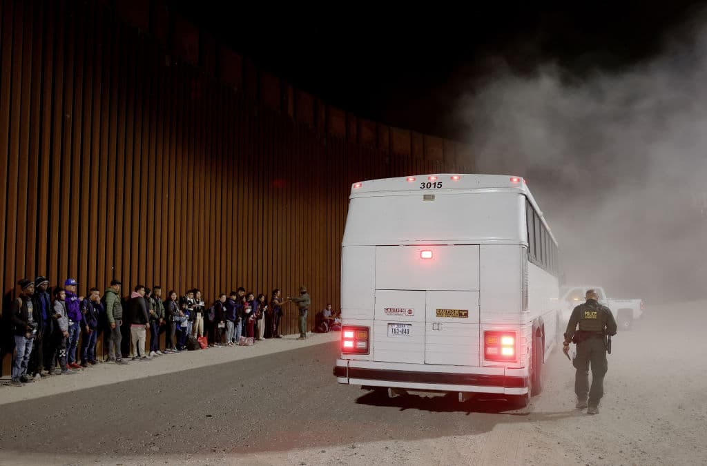 Los migrantes esperan para subir al autobús.