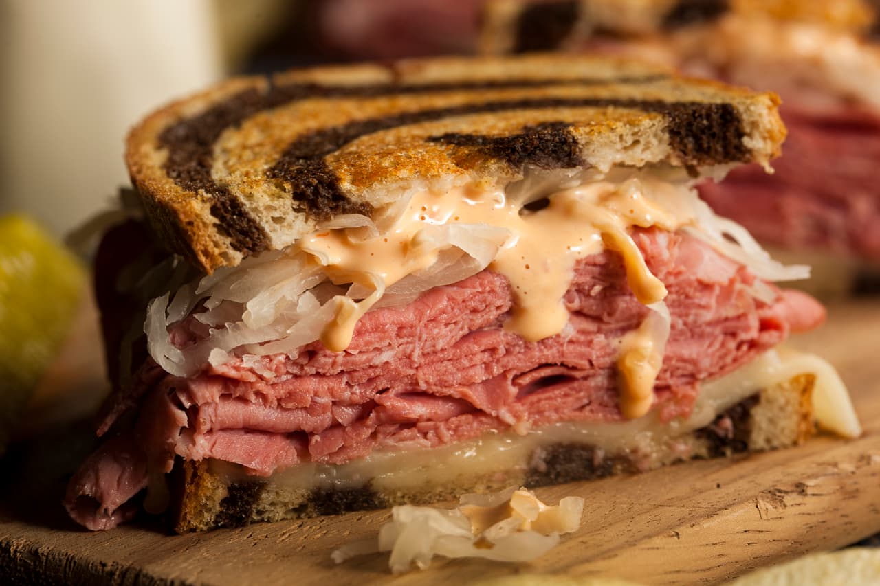 <b>Puesto 21. Reuben</b>
<br>
<br>Es un sándwich que combina carne en conserva, pan de centeno, chucrut (coles encurtidas estilo alemán), aderezo ruso y queso suizo. Según una de las muchas teorías, fue inventado en Manhattan, Nueva York en 1914. Arnold Reuben, propietario de Reuben Delicatessen, lo construyó cuando una clienta le pidió algo nuevo.
<br>
<br>Este sándwich se puede encontrar en los delis judíos porque es parte de la cultura gastronómica hebrea. Según Taste Atlas, es consumido principalmente por los judios no ortodoxos.
<br>