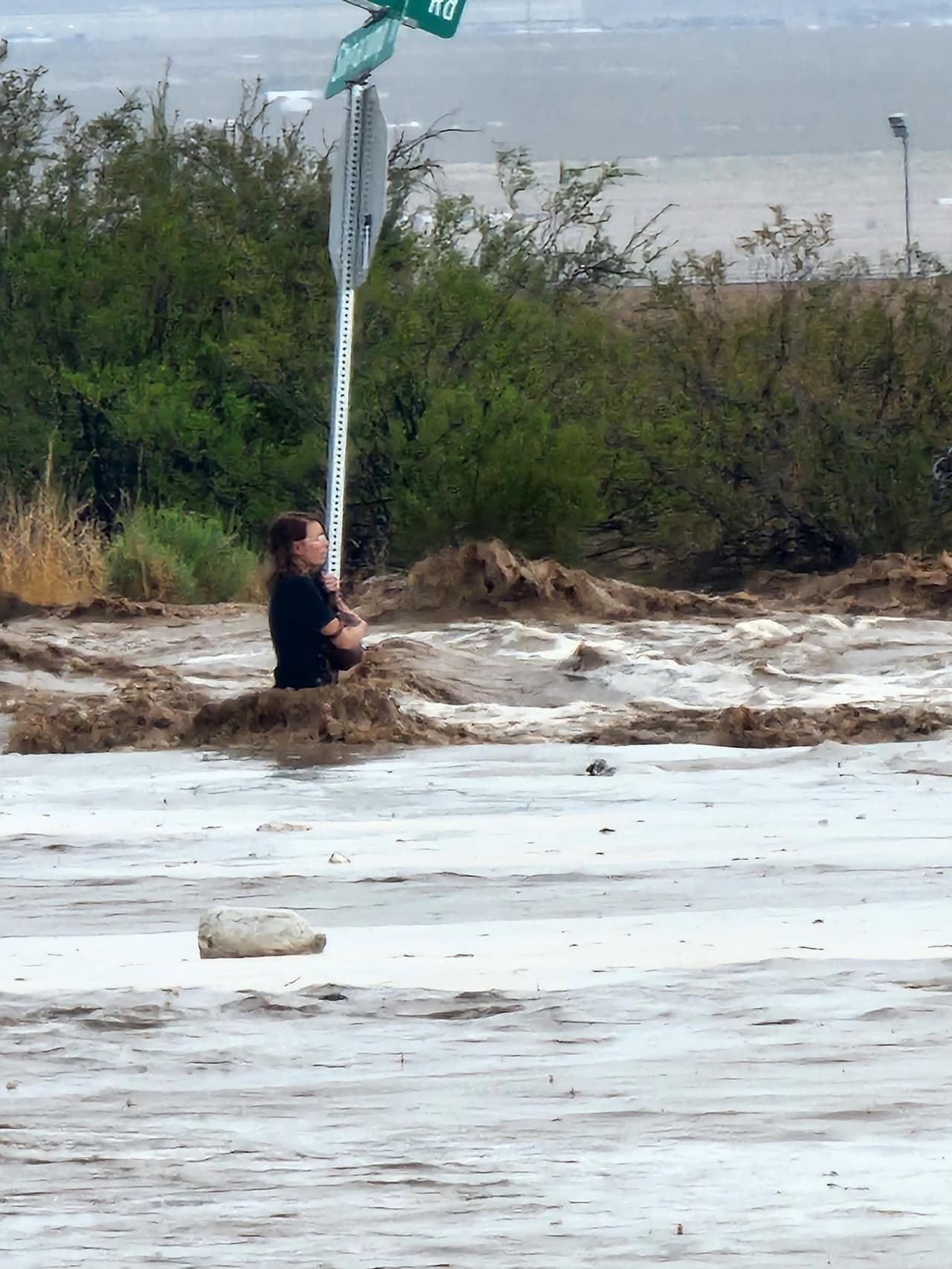 En una carretera inundada y con el agua llegándole a la cintura, la mujer se sostenía de un poste para evitar que la corriente se la llevara.