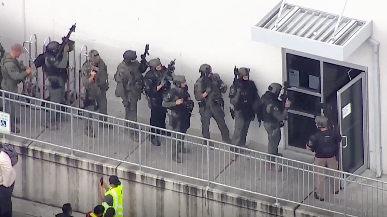 Miembros de un grupo de asalto entran por uno de los costados del inmenso almacèn de productos farmaceúticos donde ocurrió el incidente. La mujer, empleada temporal del centro de distribución, se había presentado a trabajar normalmente como cada mañana a las 9:00 AM.