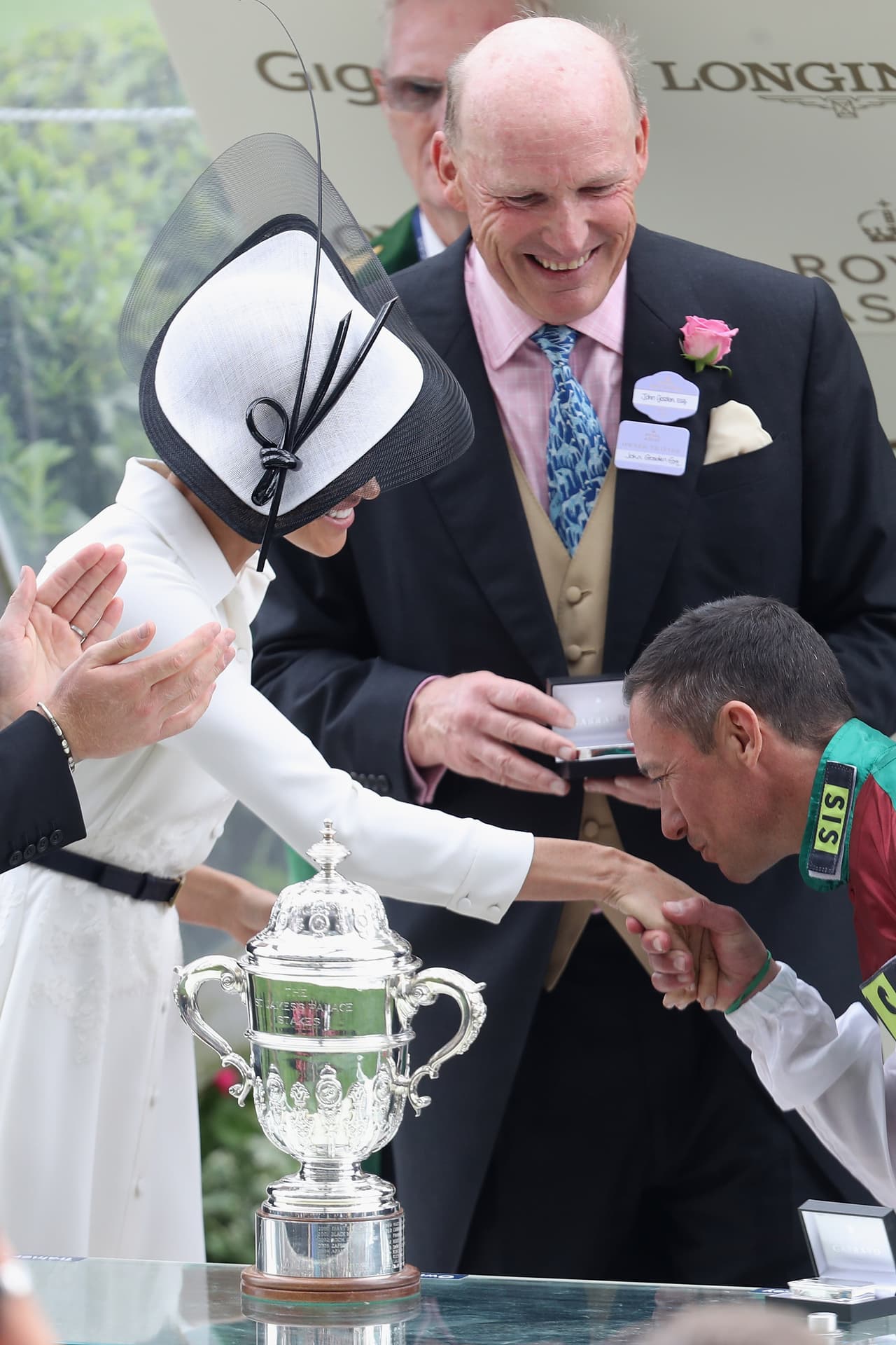 Dettori aprovechó para 
<b>besar en la mano a la duquesa,</b> un gesto al que algunos medios describieron como
<b> "<a href="http://www.dailymail.co.uk/femail/article-5860911/Prince-Harry-Meghan-Markle-join-Queen-Royal-Ascot.html">audaz</a>"</b>, aunque simpático, a juzgar por la reacción de la audiencia.