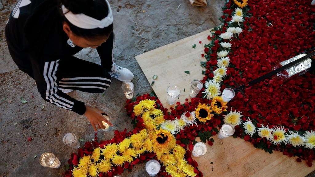 Family members carefully collect sunflowers, petals to be buried atop the grave of Luz Maria Gonzalez, during her cross raising ceremony in the family home in Valle de Chalco, on the outskirts of Mexico City, Friday, July 3, 2020.
