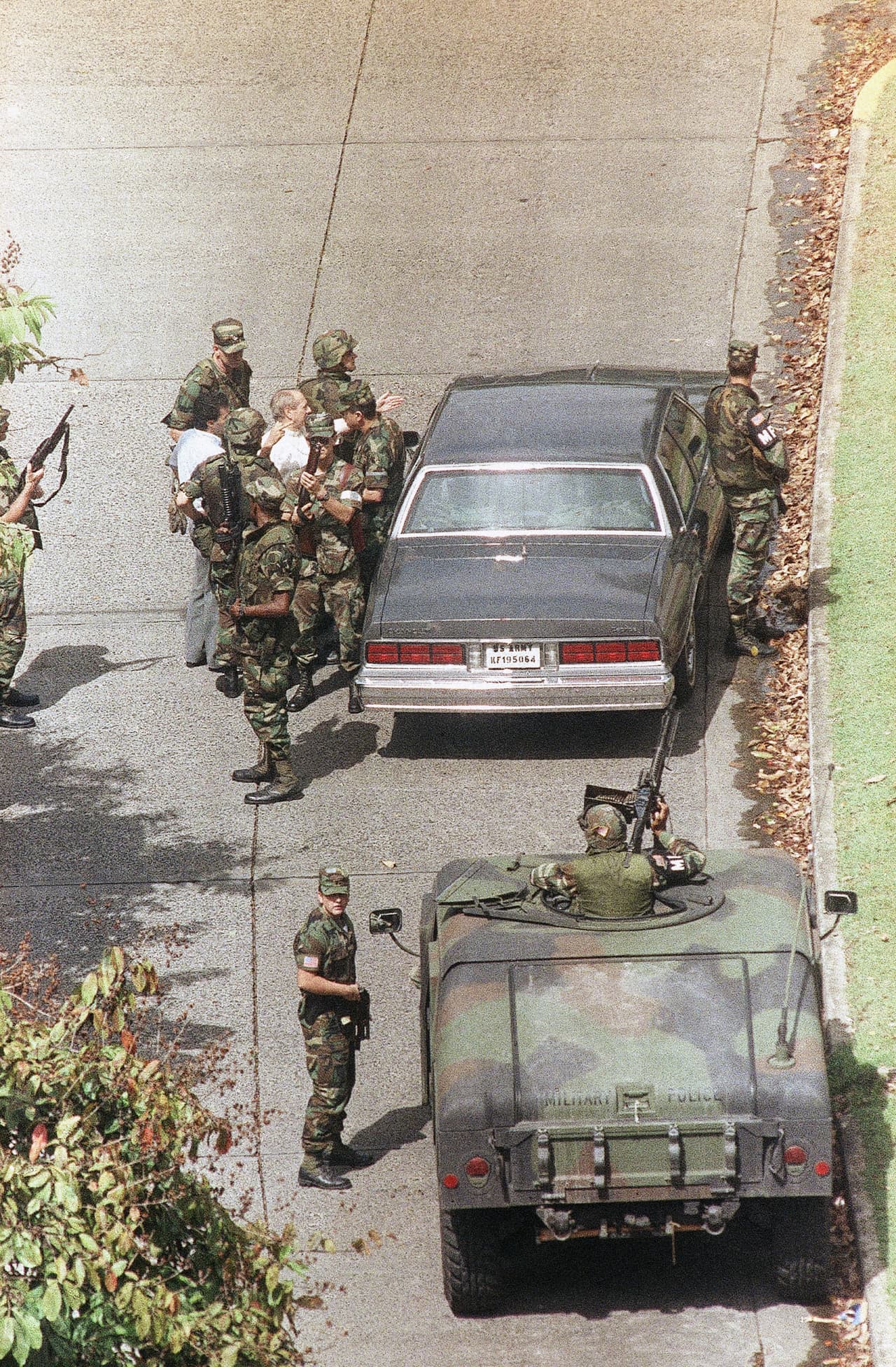 Javier Villanueva, asistente del embajador del Vaticano, en camisa blanca, arriba a la izquierda, habla con el general Maxwell Thurman, jefe del Comando Sur de los EEUU. Arriba a la izquierda con la espalda al automóvil, en la Embajada del Vaticano en la ciudad de Panamá, el 26 de diciembre. 1989 mientras continúan las negociaciones sobre Manuel Noriega.