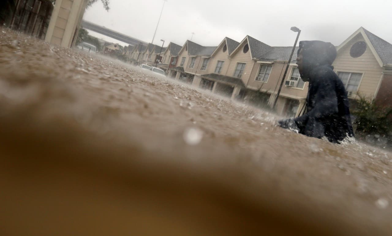 Un chico se abre paso en una calle inundada, en un complejo de apartamento de Houston.