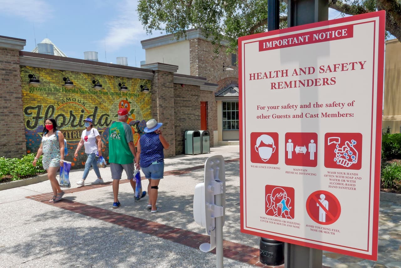 Letreros recuerdan a los clientes que deben usar máscaras y otros protocolos debido a la pandemia de coronavirus mientras pasean por el complejo de compras, restaurantes y entretenimiento de Disney Springs en Lake Buena Vista, Florida.