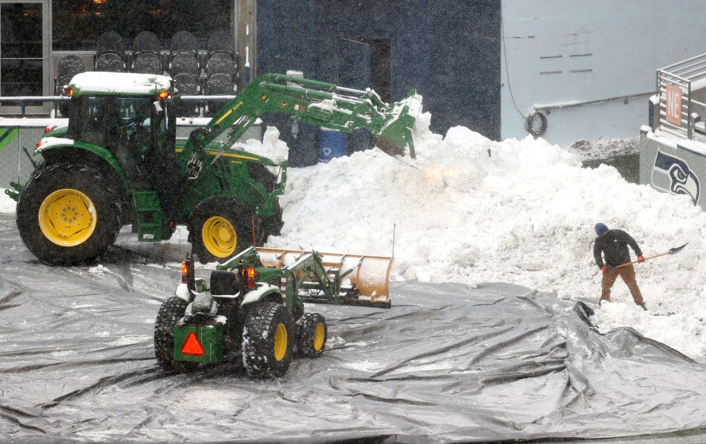 Hombres trabajan en la remoción de montañas de nieve sobre el estadio Lumen Field, en Seattle.