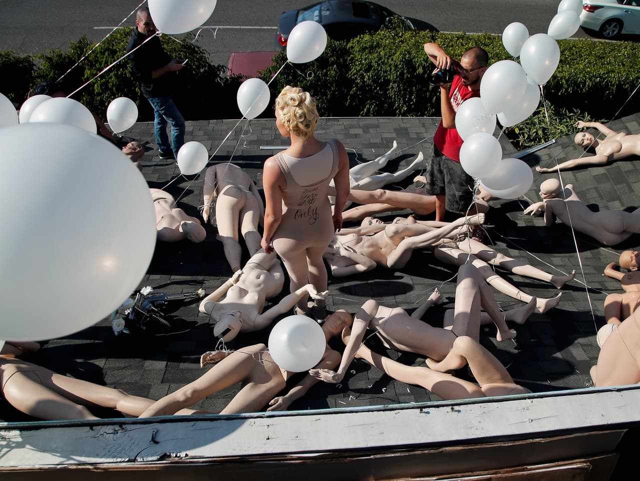 La cantante Sasha Gradiva posa para una fotografía entre los maniquíes, sobre el tejado de la casa del artista. La instalación incluye mensajes como "Nadie está seguro" y "Black Lives Matter"