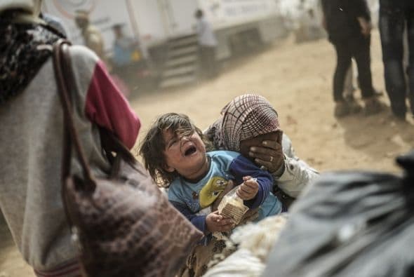 Un pequeño llora mientras sus familiares cargan consigo todo lo que pueden en su cruce a Turquía.