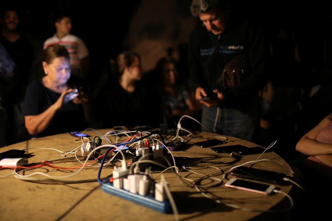 Personas usan un camión de la municipalidad para recargar las baterías de sus teléfonos móviles. "Siento indignación. No se hicieron los correctivos necesarios y es más de lo mismo", dijo a la AFP Eurimar Güere, de 36 años, tras salir de su oficina en el este de Caracas.