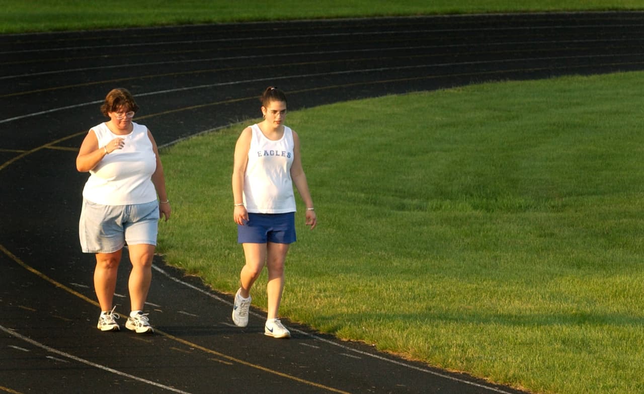 Susan Hedrick along with her daughter, Niki Hedrick, walk around the track at Brown County High School in Nashville, Ind., Friday, June, 11, 2004. They are trying to shed a combined 180 pounds, excess weight they've packed on through a sedentary lifestyle filled with fast-food and too much TV time. They've been eating healthier and taking longs walks in the effort to loose weight. (AP Photo/Darron Cummings)