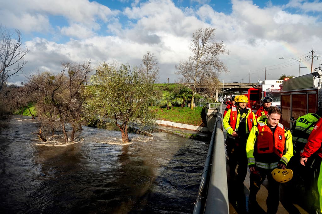 Los trabajadores de búsqueda y rescate regresan a sus vehículos después de rescatar a los residentes de un campamento para personas sin hogar rodeados por las inundaciones del río Guadalupe el domingo 4 de febrero de 2024 en San José, California. Los fuertes vientos y las fuertes lluvias están afectando la región. (Foto AP/Noah Berger)