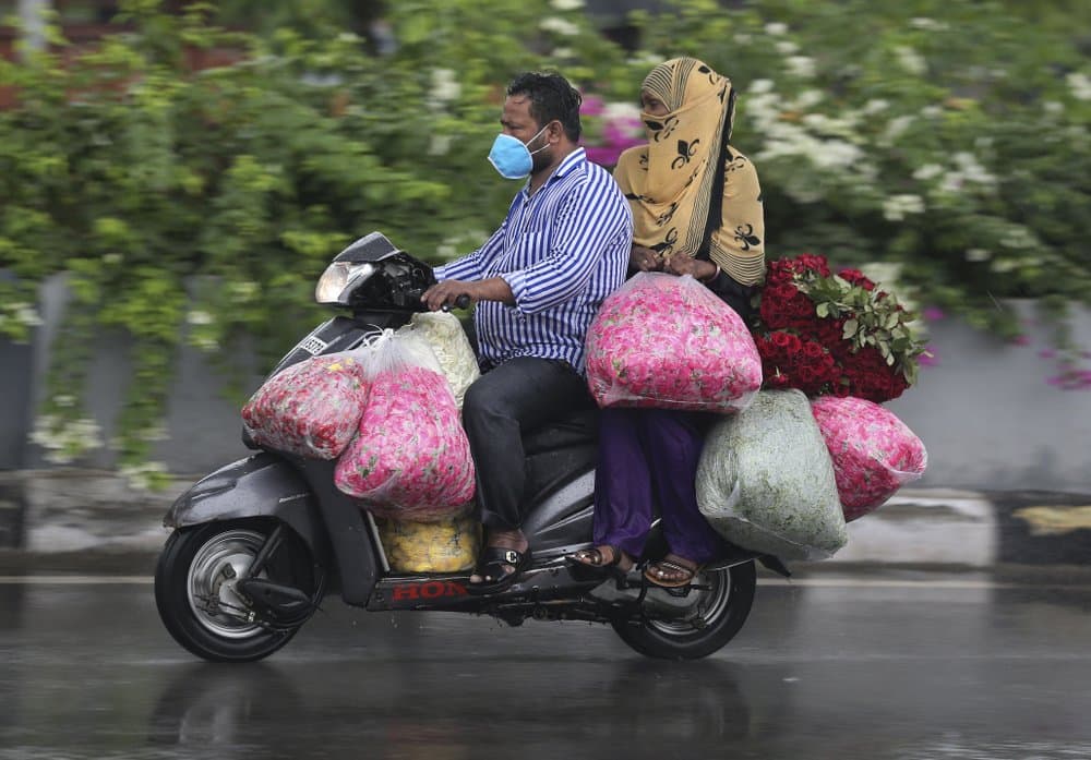 Un hombre indio con máscara 
<b>transporta flores bajo la lluvia en Hyderabad, India, el 23 de julio de 2020.</b> India recibe sus lluvias monzónicas de junio a septiembre.
