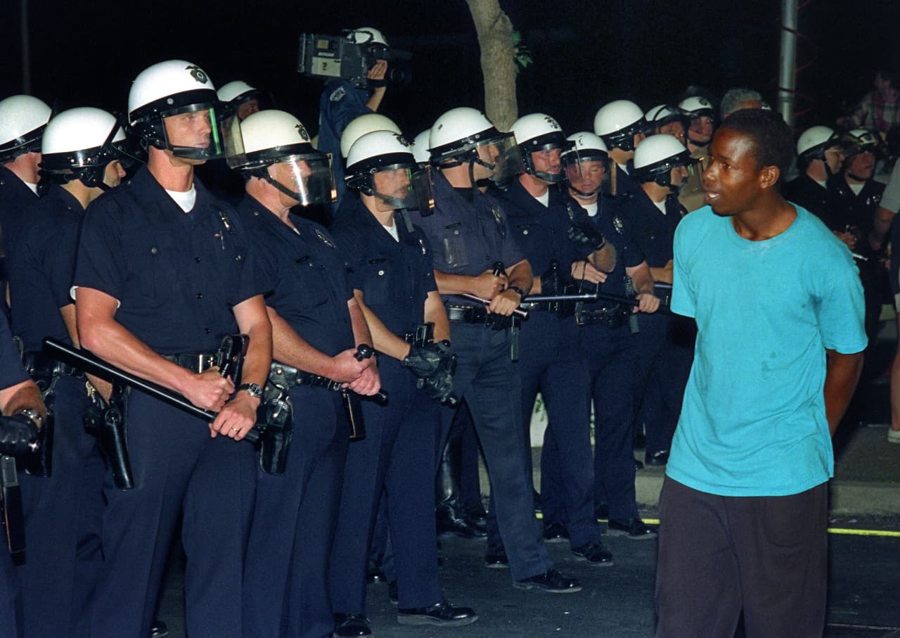 Un joven afroamericano camina frente a policías angelinos.