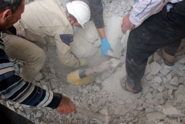 Los equipos de emergencia rescatan a un hombre enterrado bajo los escombros después de que un edificio colapsara después de un ataque bomba reportado en la ciudad siria de Alepo.