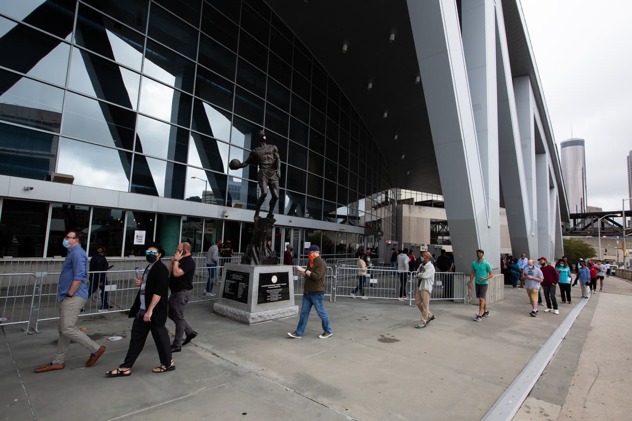 Los votantes esperan a las afueras del State Farm Arena para emitir sus votos en el primer día de votación anticipada en Georgia.
