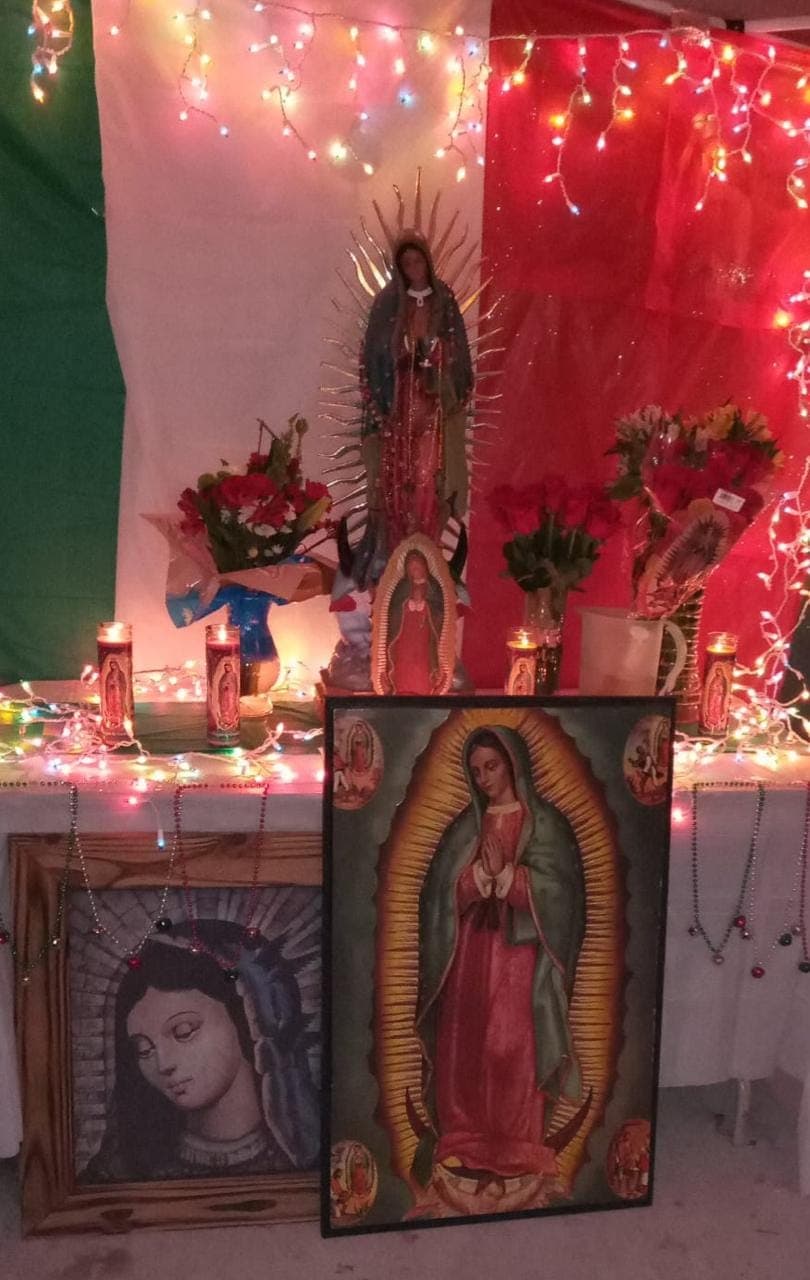 La ofrenda a la Virgen de Guadalupe en la casa de Yadira Chávez fue decorada con luces cascada de navidad y una bandera de México de fondo.