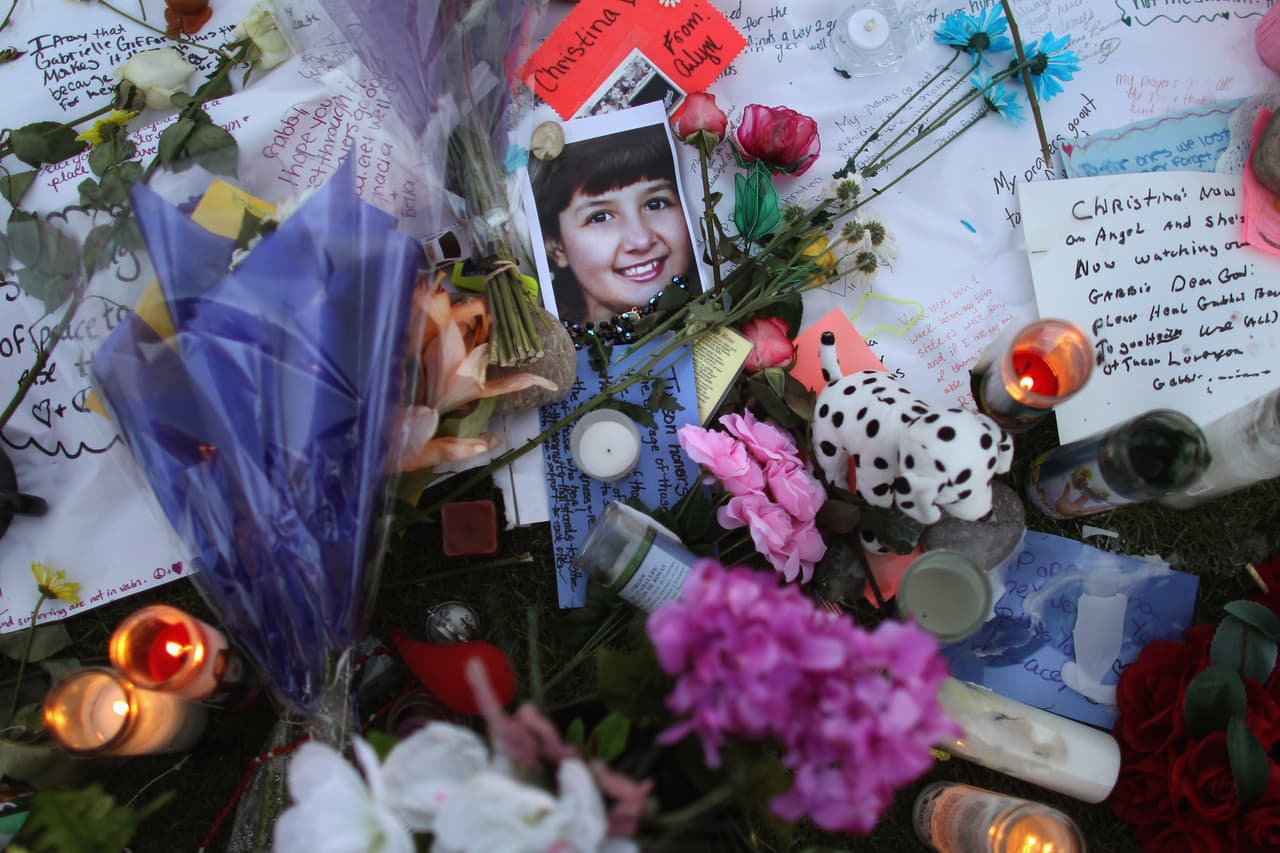 <b>2011. Reunión comunitaria en un centro comercial de Tucson, Arizona 2011</b>. Jared Lee Loughner, de 23 años, disparó con una pistola Glock a los asistentes a una reunión de ciudadanos con la congresista demócrata Gabrielle Giffords en un centro comercial. En el tiroteo murieron seis personas, incluidos el juez federal John McCarthy Roll y una niña de nueve años. 
<a href="https://elpais.com/internacional/2011/01/08/actualidad/1294441215_850215.html">La congresista Giffords, el blanco principal del ataque, resultó herida. Loughner fue detenido por los propios testigos y condenado a cadena perpetua.</a> En la fotografía, un altar conmemorativo de las víctimas con la imagen de Christina Taylor-Green, la pequeña que falleció en el ataque. 8 de enero de 2011.