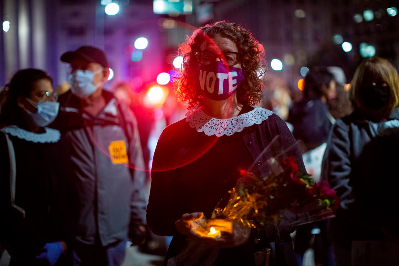 Una mujer honra la memoria de la juez mientras usa una máscara que dice "Vota"
