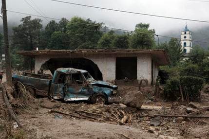A pickup truck lays destroyed next to a house damaged by a mudslide in Xaltepec, on the mountainous north of Puebla state, Mexico, Sunday, Aug. 7, 2016. The death toll from the remnants of Hurricane Earl grows to more than 30 in Mexico as a new tropical storm forms off the country's Pacific Coast.