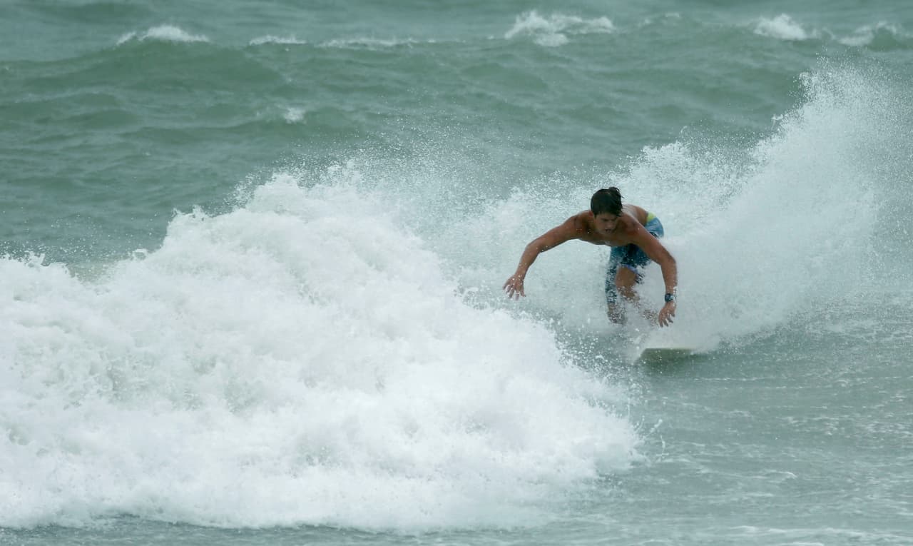 Algunos aprovechan las fuertes olas que trajo la tormenta para practicar surf