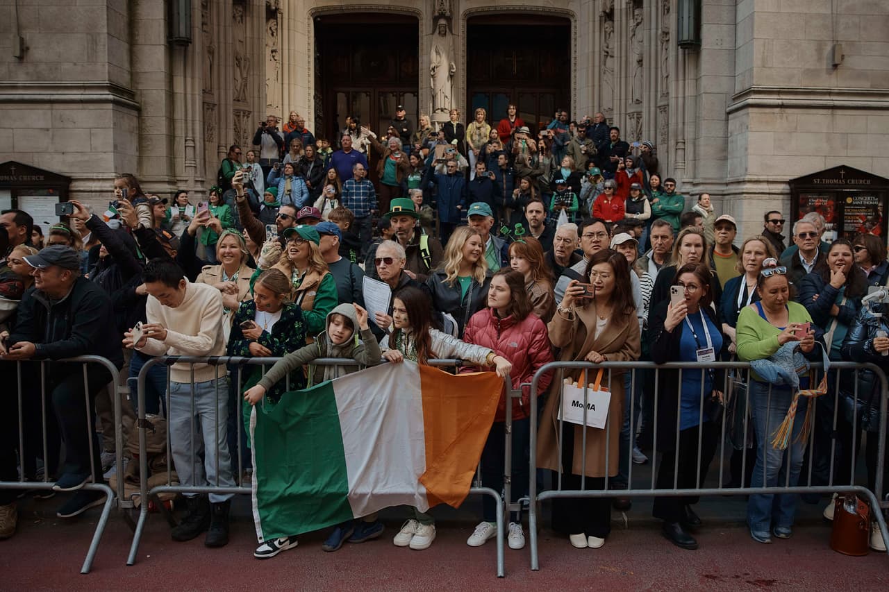 Asistentes al Desfile del Día de San Patricio sostienen una bandera irlandesa.