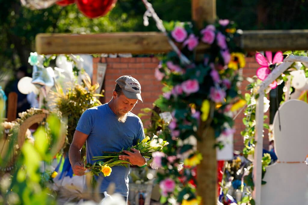 Un hombre coloca flores mientras presenta sus respetos en un monumento fuera de la escuela Robb. 
<a href="https://www.univision.com/local/san-antonio-kwex/cruces-town-square-robb-elementary-uvalde-victimas-tiroteo-fotos">En Uvalde Town Square también hay 21 cruces. </a>