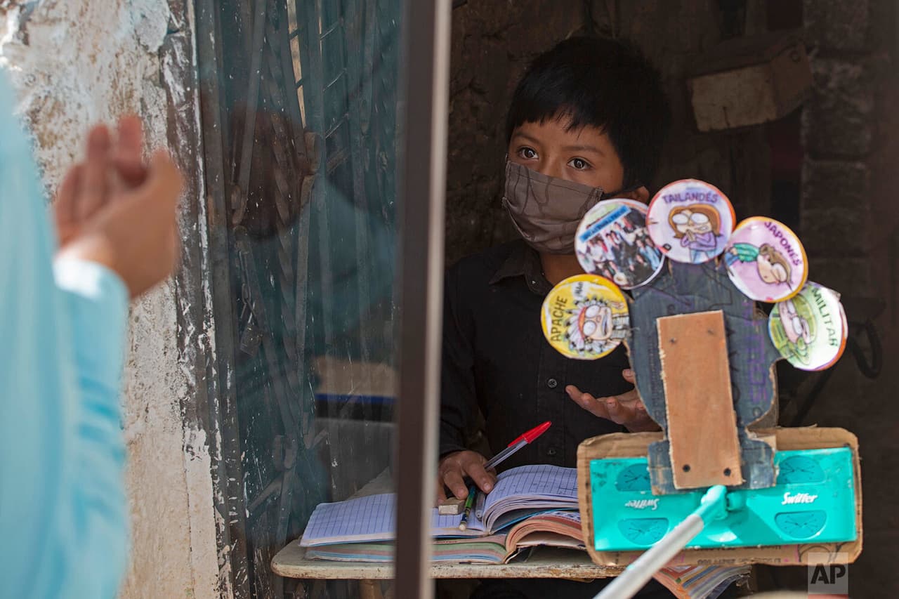 Óscar Rojas, de 11 años, escucha a su maestro Gerardo Ixcoy, estacionado en un aula a las afueras de su casa en Santa Cruz del Quiché, Guatemala. 
<b>La pandemia realmente ha alterado su rutina "porque ahora no estoy recibiendo clases normales", dijo Óscar. </b>