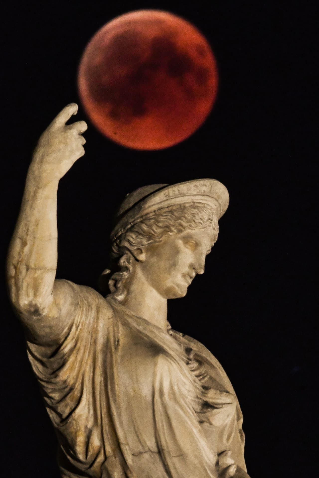"Luna de sangre" junto a una estatua de la antigua diosa griega Hera en el centro de Atenas.