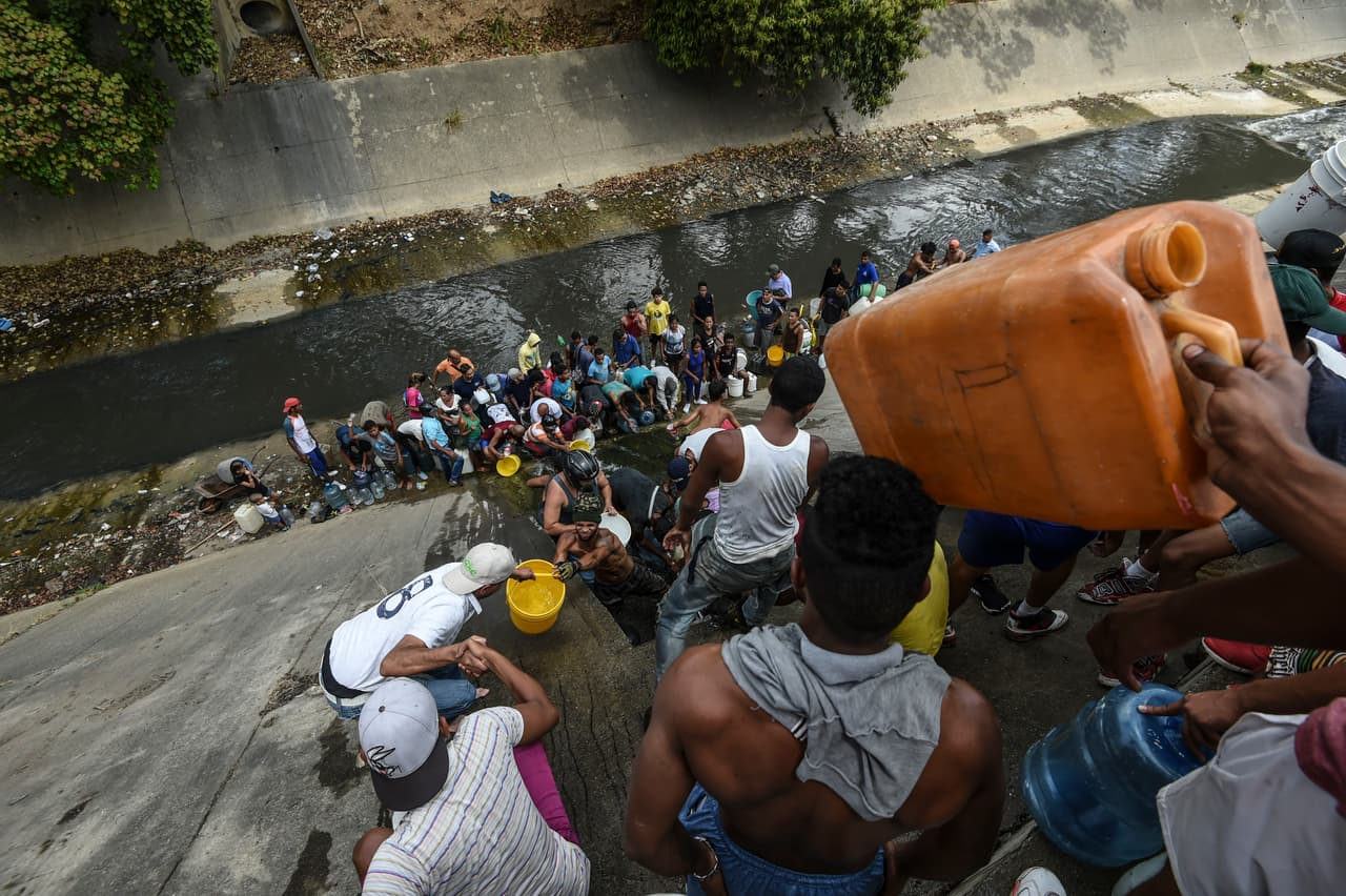 Algunos residentes recolectan de un afluente del río Guaire en Caracas. Este río contaminado con aguas residuales recorre la capital de este a oeste.