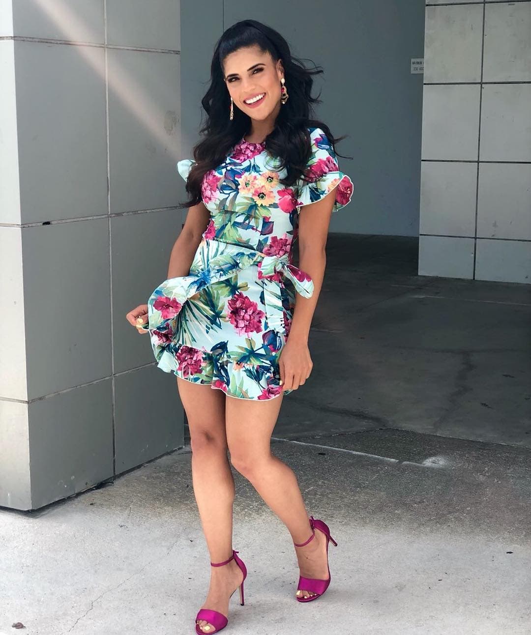 ¿Qué te parece este look con aires más tropicales? El estampado floral es la alternativa ganadora de la temporada, mira lo linda que se ve la dominicana con volantes en las mangas, listones en la cintura y vuelos en la parte baja de la falda.
<br>