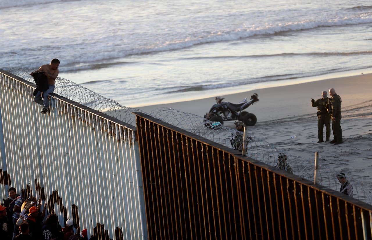 Un migrante sobre la valla fronteriza, ahora reforzada con alambres de púas.
