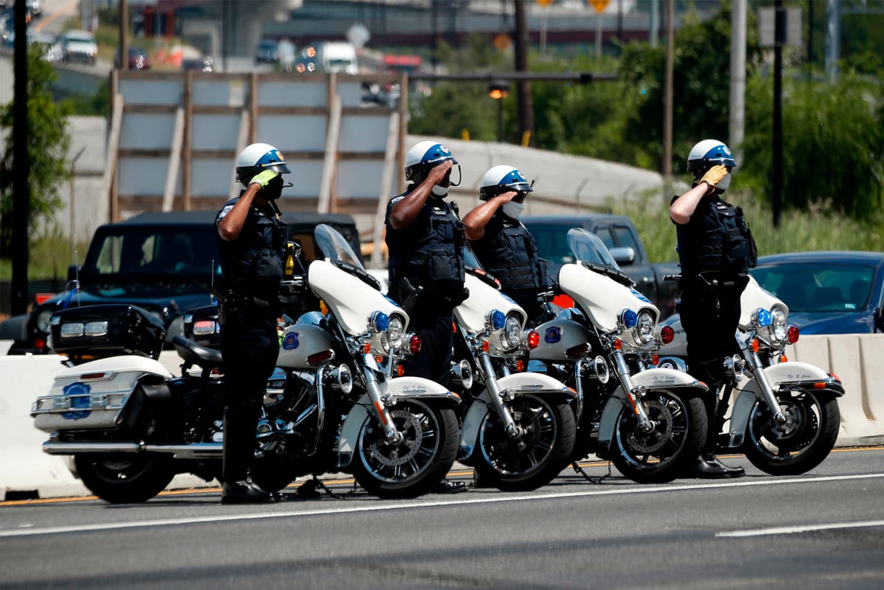Oficiales del departamento de policía de de la capital, saludan la caravana con los restos del excongresista.