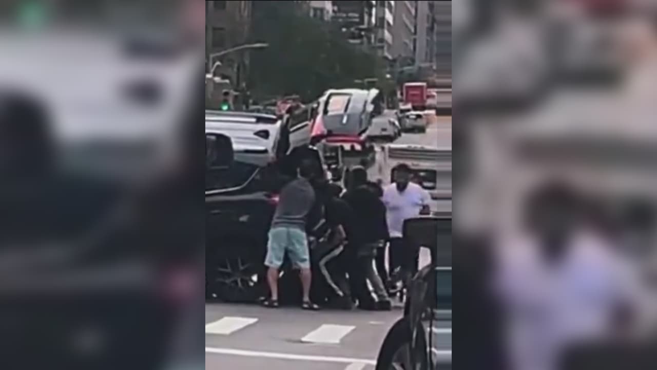 Hombres levantan auto para salvar a una mujer que había quedado atrapada en plena calle de Nueva York