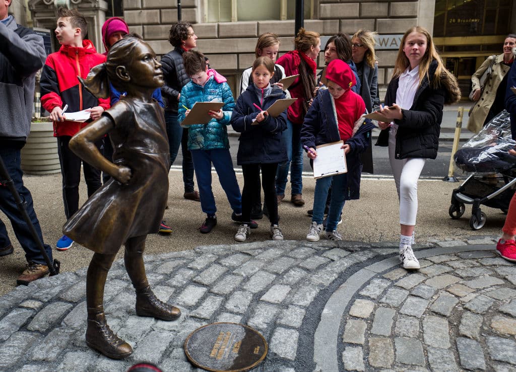 Un grupo de estudiantes de sexto grado de The Blue School, en Nueva York, toman notas frente a la estatua de la 'niña desafiante'. (Getty Images)