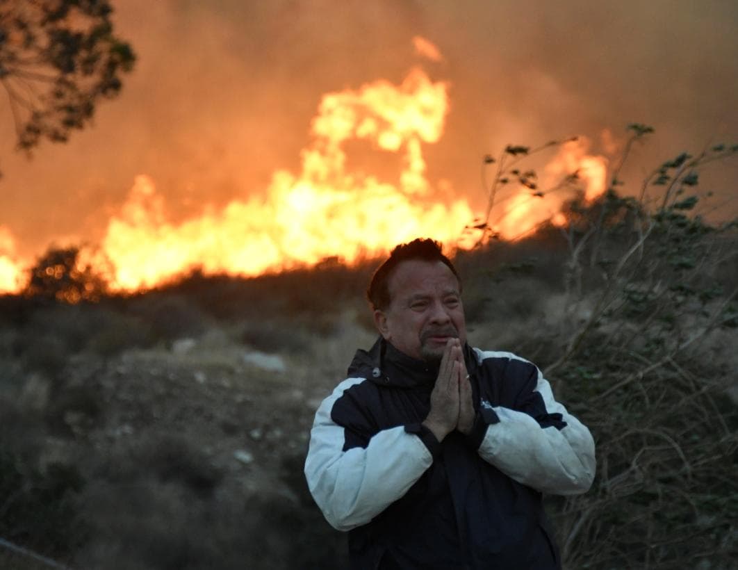 Un hombre reza junto al fuego Creek mientras este se propagaba por el valle de San Fernando, en el noreste de Los Ángeles.