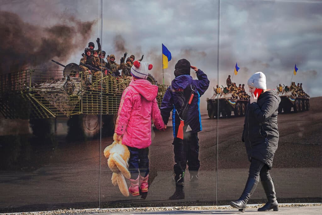 Una mujer pasea frente a un mural fotográfico que recuerda la anterior invasión de Rusia a Ucrania, en 2014. El ataque se este jueves ha hecho caer en picado los 
<a href="https://www.univision.com/noticias/dinero/mercados-internacionales-precio-petroleo-wall-street-invasion-rusia-ucrania">mercados internacionales y ha empujado los precios del petróleo por encima de los 100 dólares el barril</a>.
