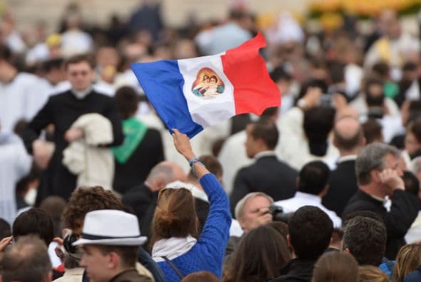 Una peregrina francesa en la Plaza de San Pedro alza una bandera de su país con la imagen de la Virgen María.
