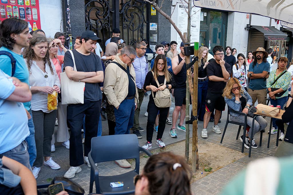 Personas reunidas alrededor de una radio portátil colocada en un árbol en una calle de Madrid para escuchar las noticias.