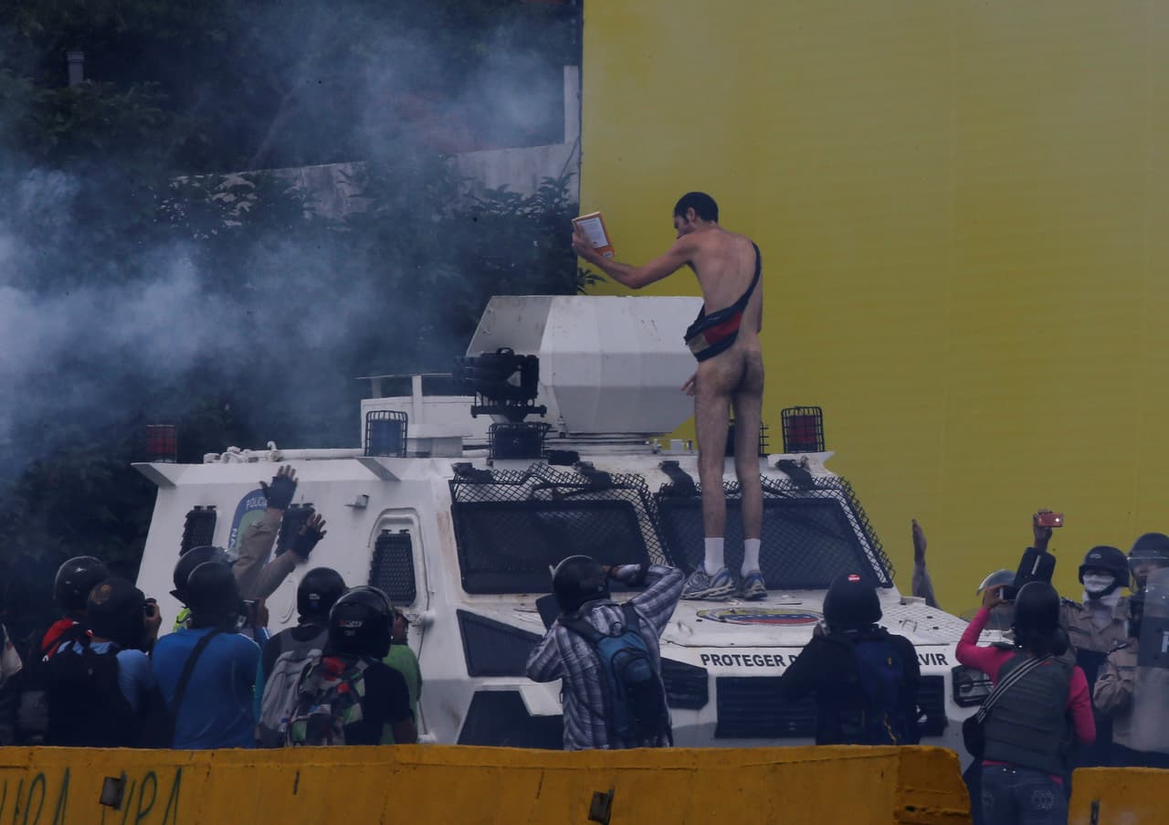 After stopping in front of an armored police vehicle he climbed onto its hood. "Get down!" the police shouted at him. (Carlos García Rawlins/Reuters)