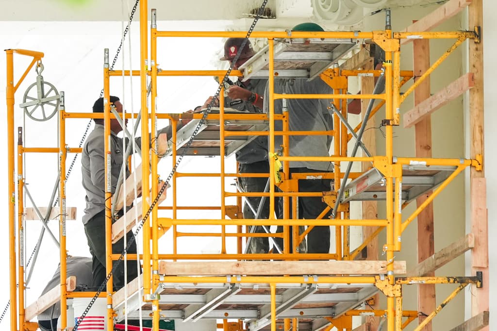 Empleados del Servicio de Parques Nacionales trabajan en un andamio en el pórtico.