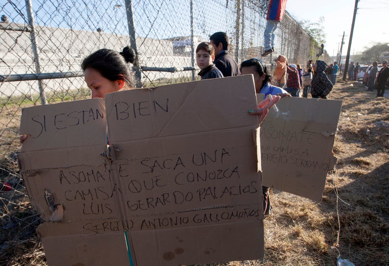 Familiares con pancartas piden señales de vida de sus familiares internos.