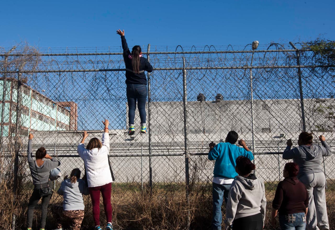 Parientes de los reos de la cárcel de Topo Chico suben una reja que rodea el centro para ver si pueden ver a sus familiares.