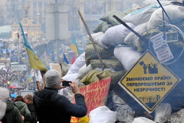 Un hombre toma una foto de un cartel que se lee "Cambio del país , lo siento por las molestias" en una barricada en la Plaza de la Independencia en Kiev.