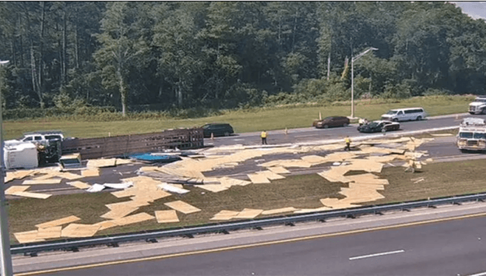 Camión vuelca y tira láminas de madera sobre carretera