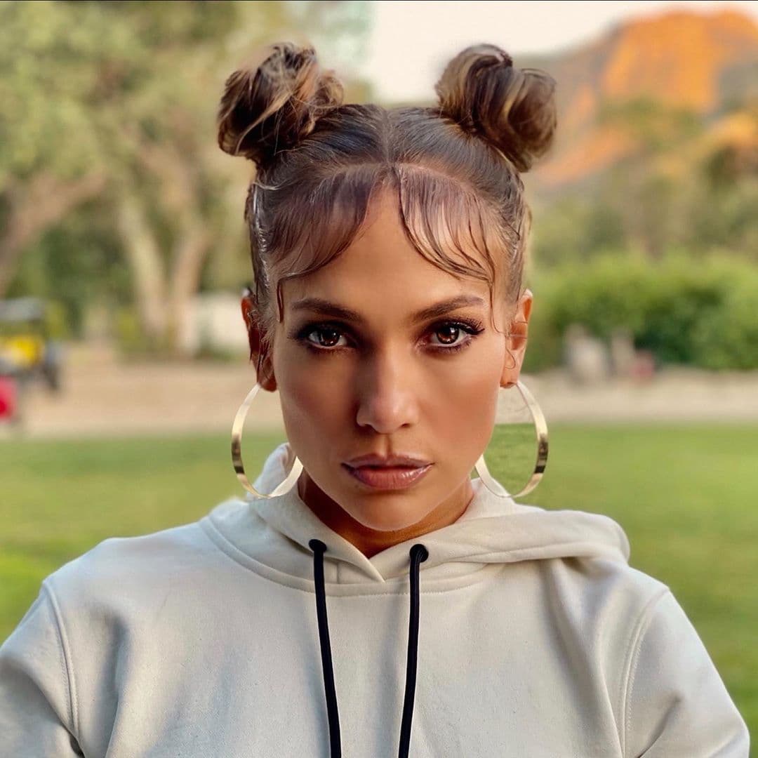 Jennifer Lopez es una de las celebridades más auténticas en redes sociales y en ellas nos ha sorprendido con sus looks diferentes, originales y divertidos. Uno de los peinados que han llamado más la atención fue el de esta imagen que ella misma llamó 'baby hair and moñitos' (pelo de bebé y moñitos).