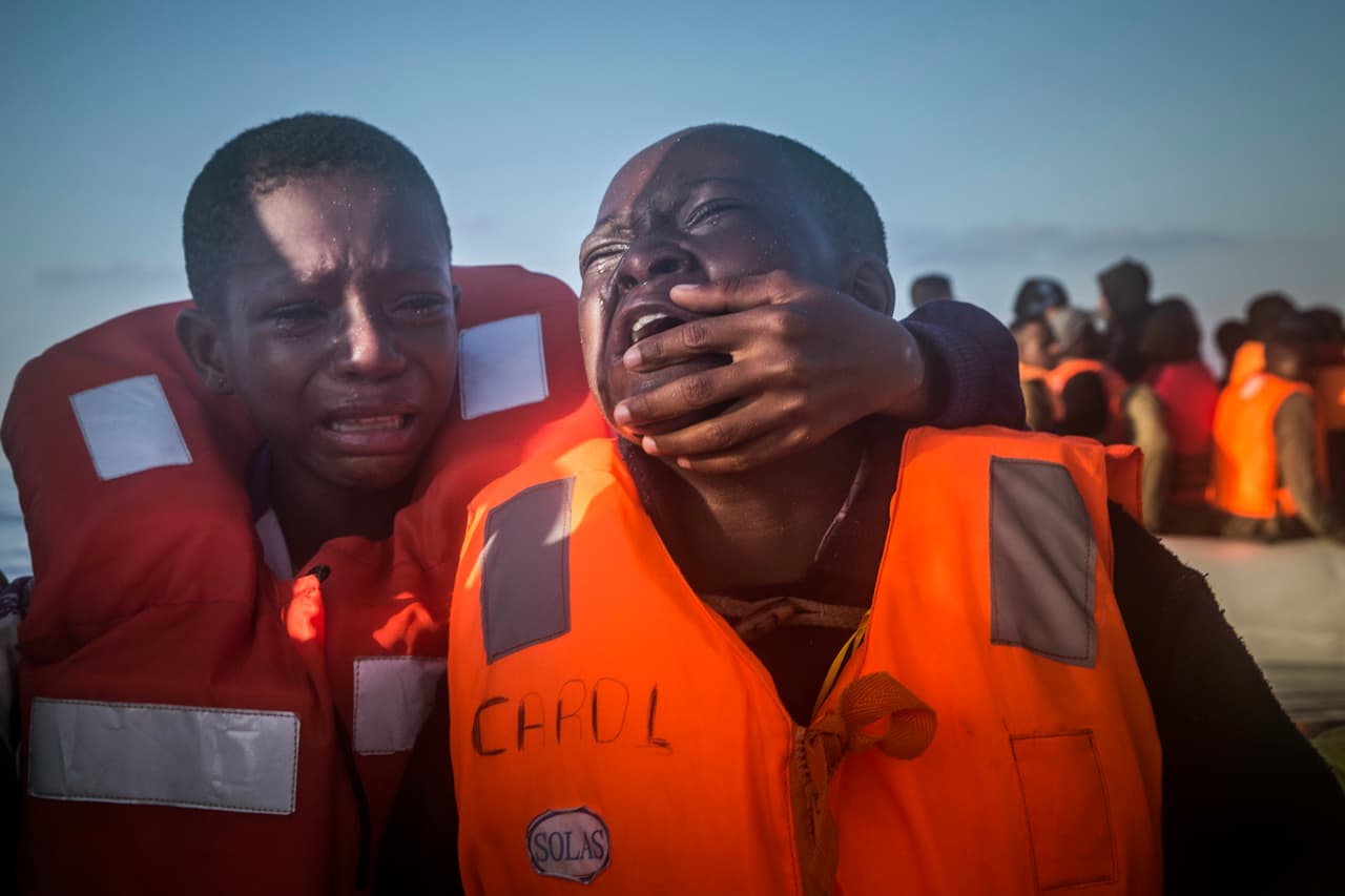 Dustin, un pequeño de 11 años proveniente de Nigeria, llora junto a su hermano luego de perder a su madre en un naufragio frente a las costas de Libia, el 28 de julio de 2016.
