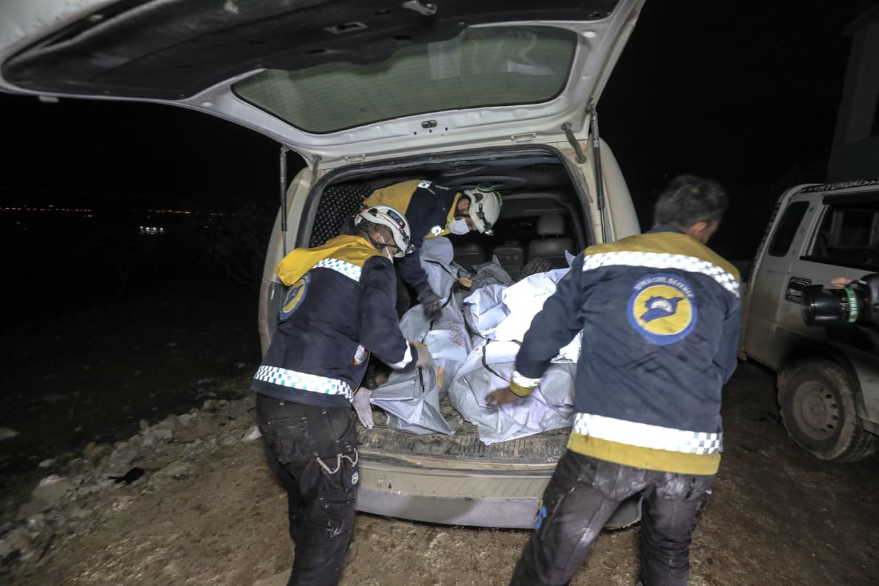 Miembros de la defensa civil de Siria cargan los cuerpos sin vida despúes del ataque estadounidense en la madrugada.